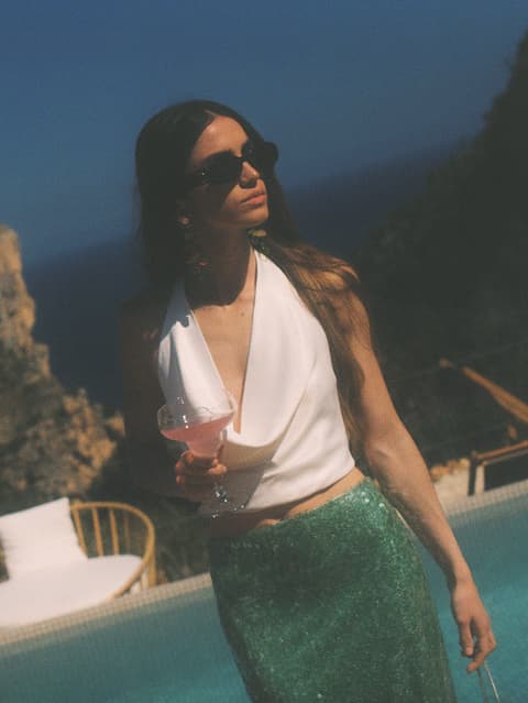 Escena de dona amb una copa al costat de piscina