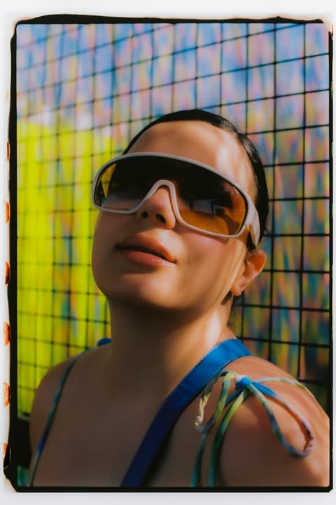 Retrato mujer con gafas grandes y fondo enrejado, estilo de agencia creativa Barcelona Victor Lecha