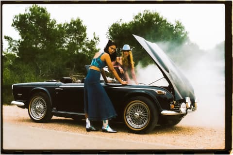 Escena cinematográfica de dos mujeres arreglando un automóvil clásico